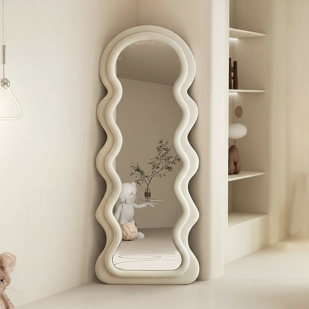 Decorative standing mirror with wavy design on a neutral background