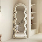 Decorative standing mirror with wavy design on a neutral background