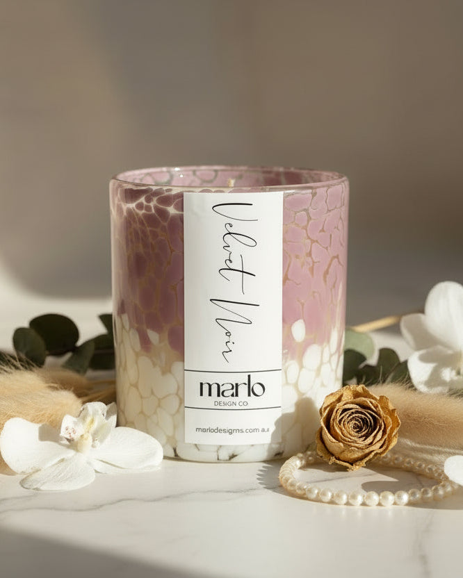 Candle with pink and white marbled design and label on a white background